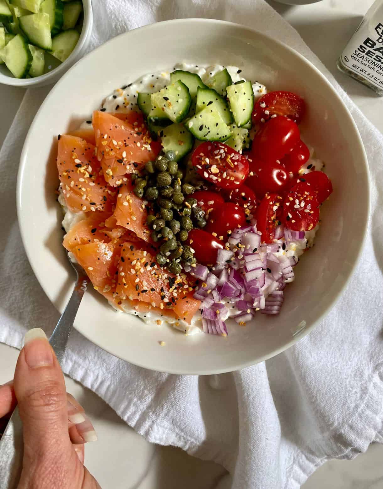 A Savory Cottage Cheese Bowl with cottage cheese, smoked salmon, diced cucmbers, sliced tomatoes, diced red onion, capers and Everything but the Bagel Seasoning.