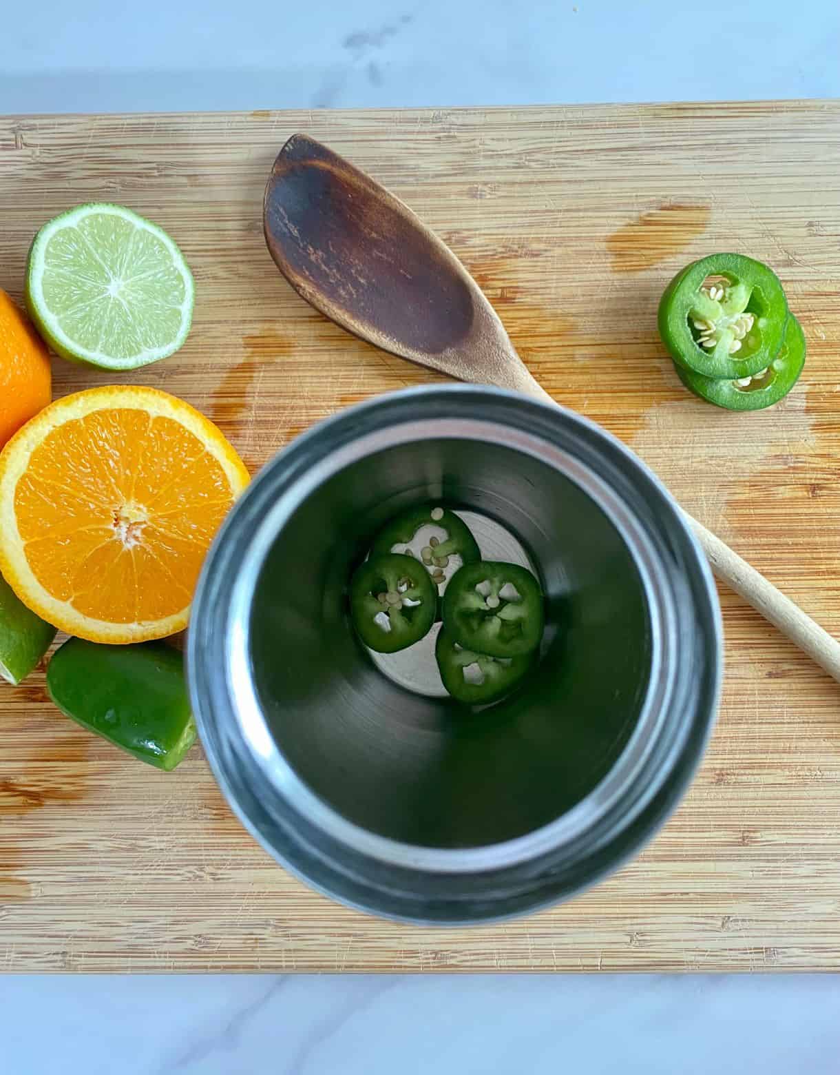 A cocktail shaker with slices of jalapeno in the bottom.