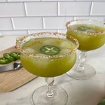Two glasses of skinny spicy margarita with a salted rim and a jalapeno slice floating in the cocktail.