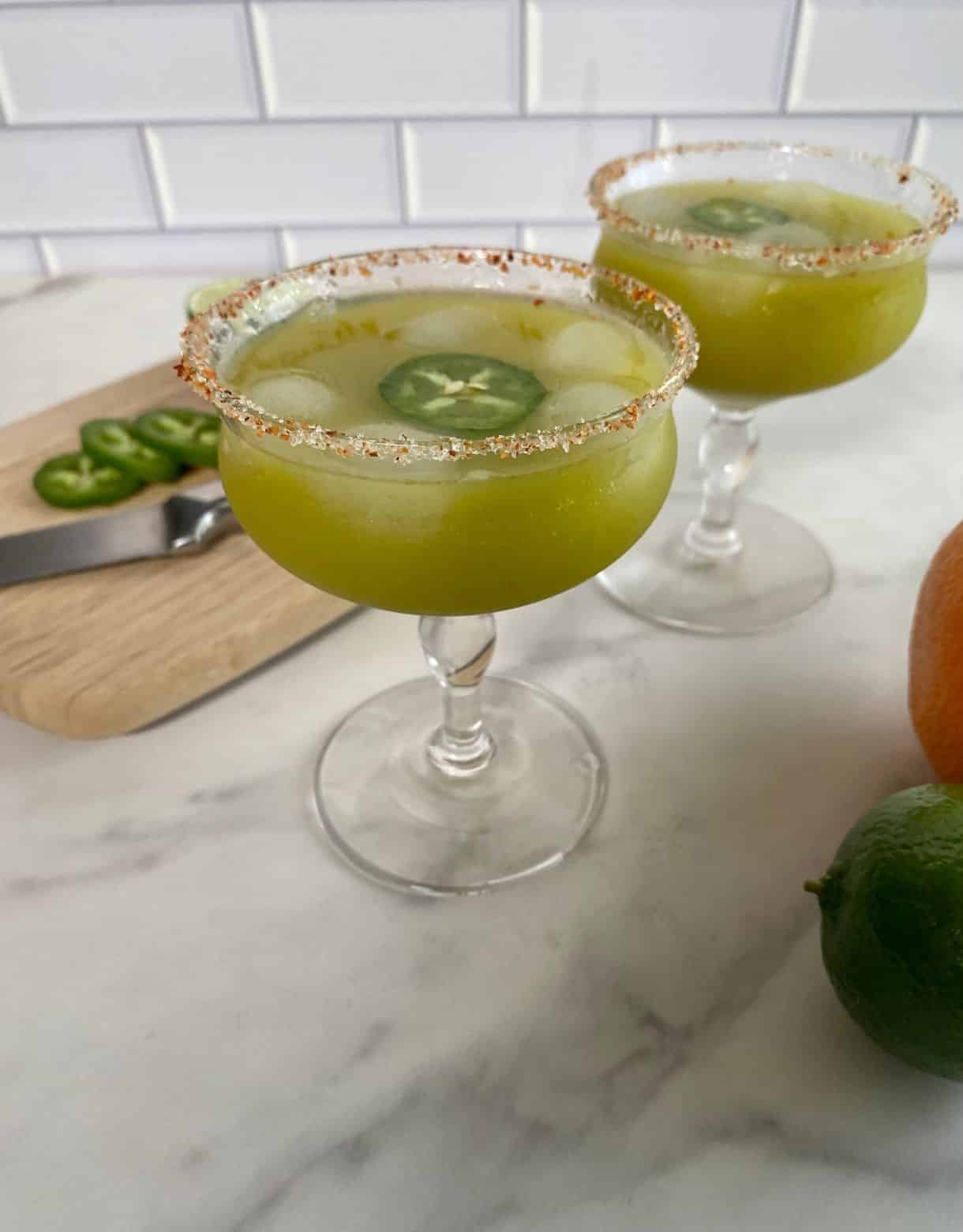 Two glasses of skinny spicy margarita with a salted rim and a jalapeno slice floating in the cocktail.
