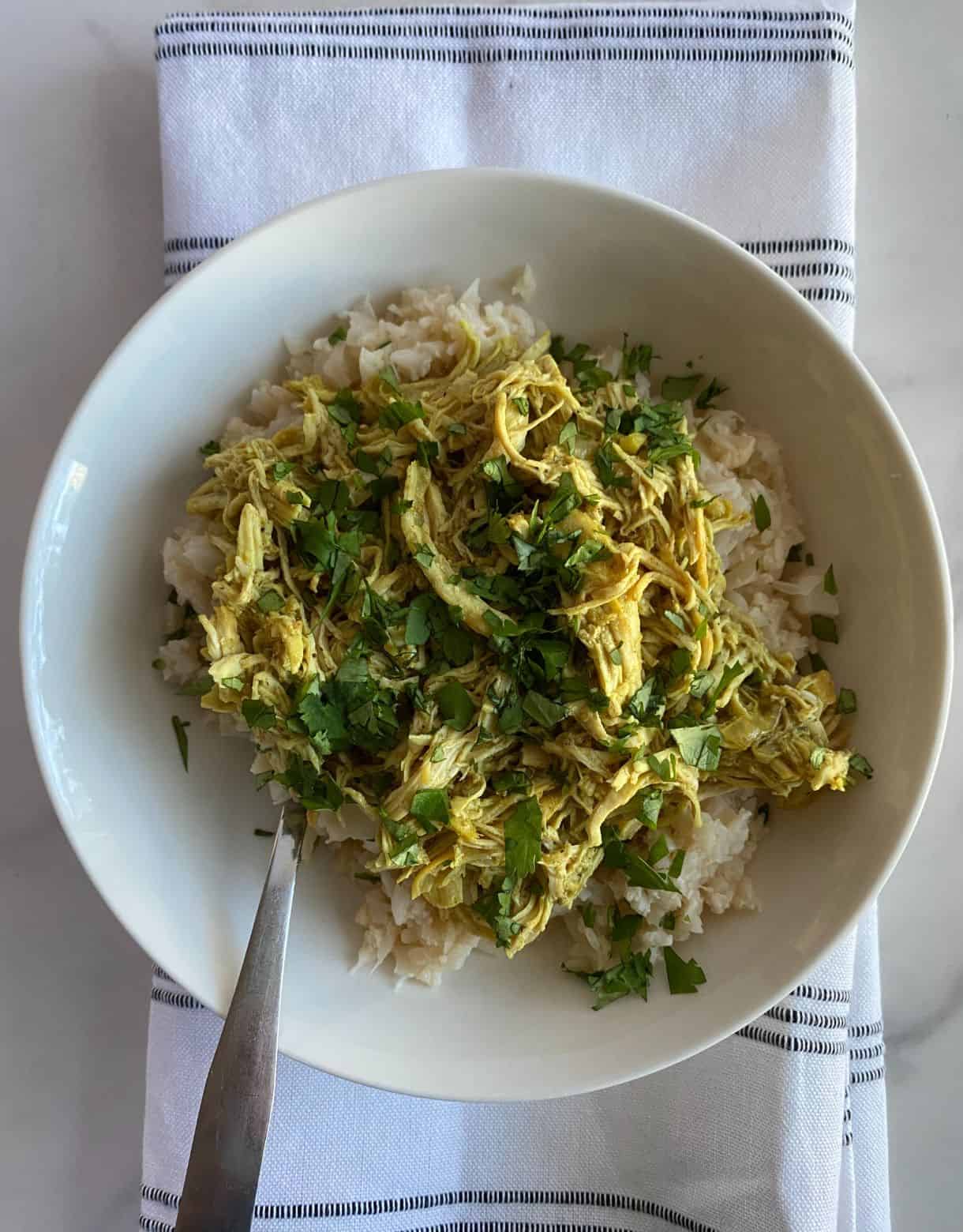 A bowl of Crockpot Chicken Curry with Coconut Milk over cauliflower rice.