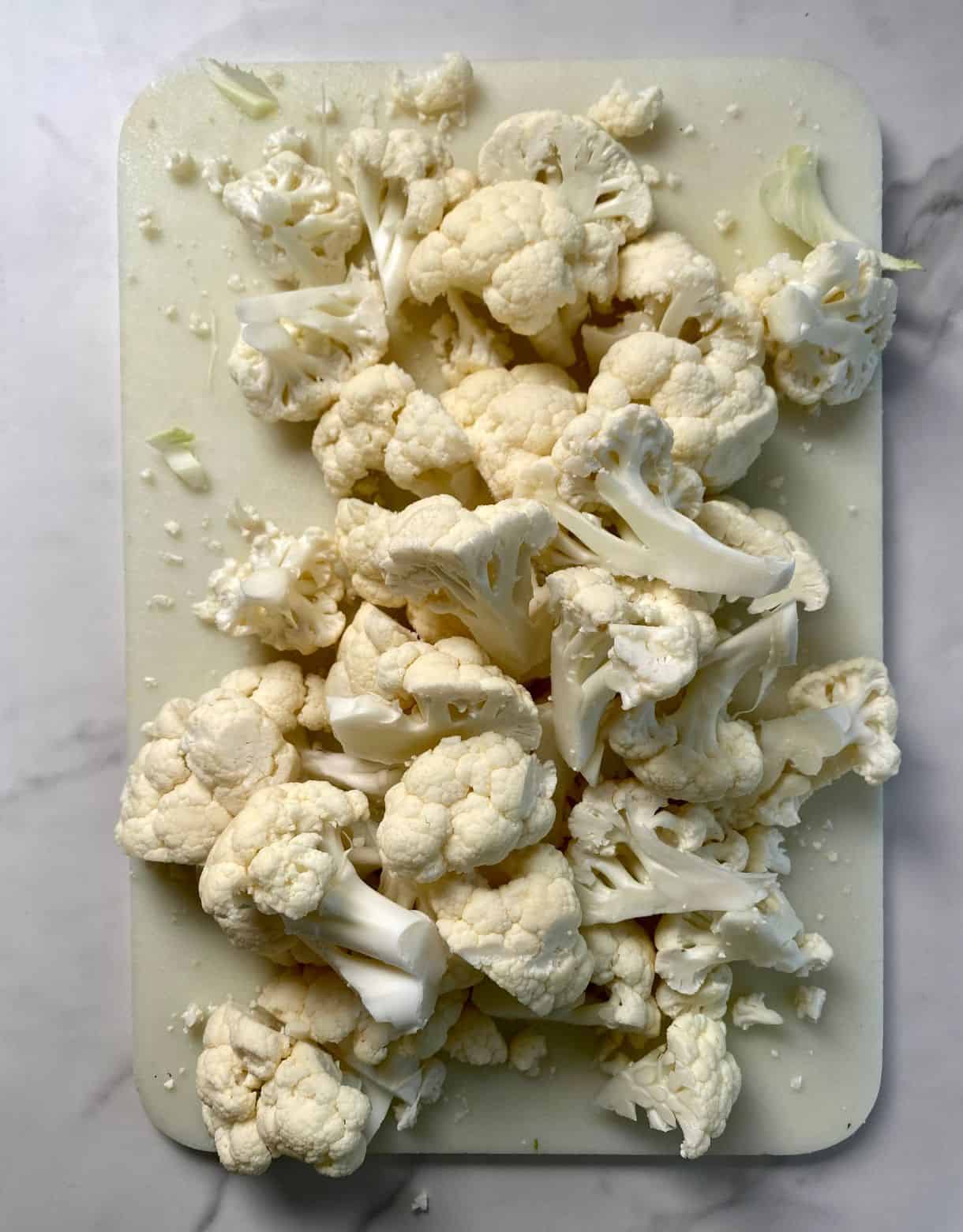 A cutting board with chopped cauliflower.