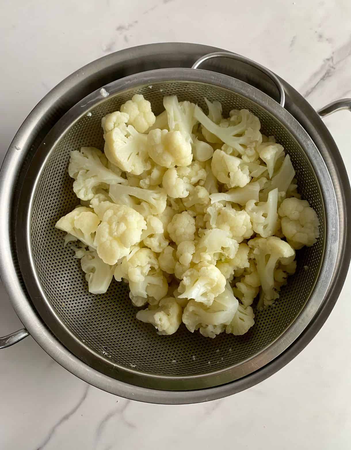 A colander with drained cooked cauliflower.