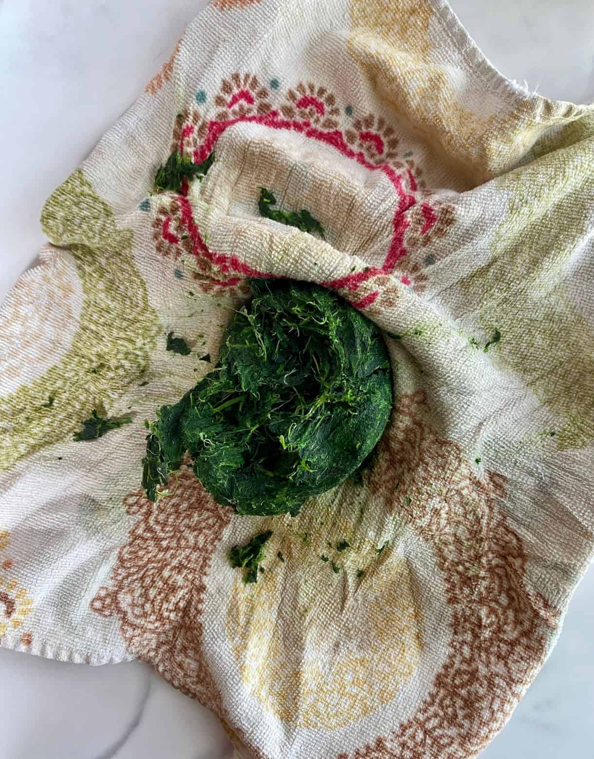 A kitchen towel with spinach squeezed in it to remove excess moisture.