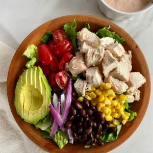 A Santa Fe Chicken Salad in a wooden bowl with a dish of Creamy Salsa Dressing.