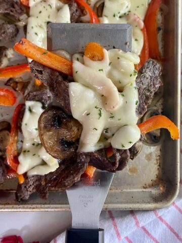 A sheet pan with cooked Philly Cheesesteaks.