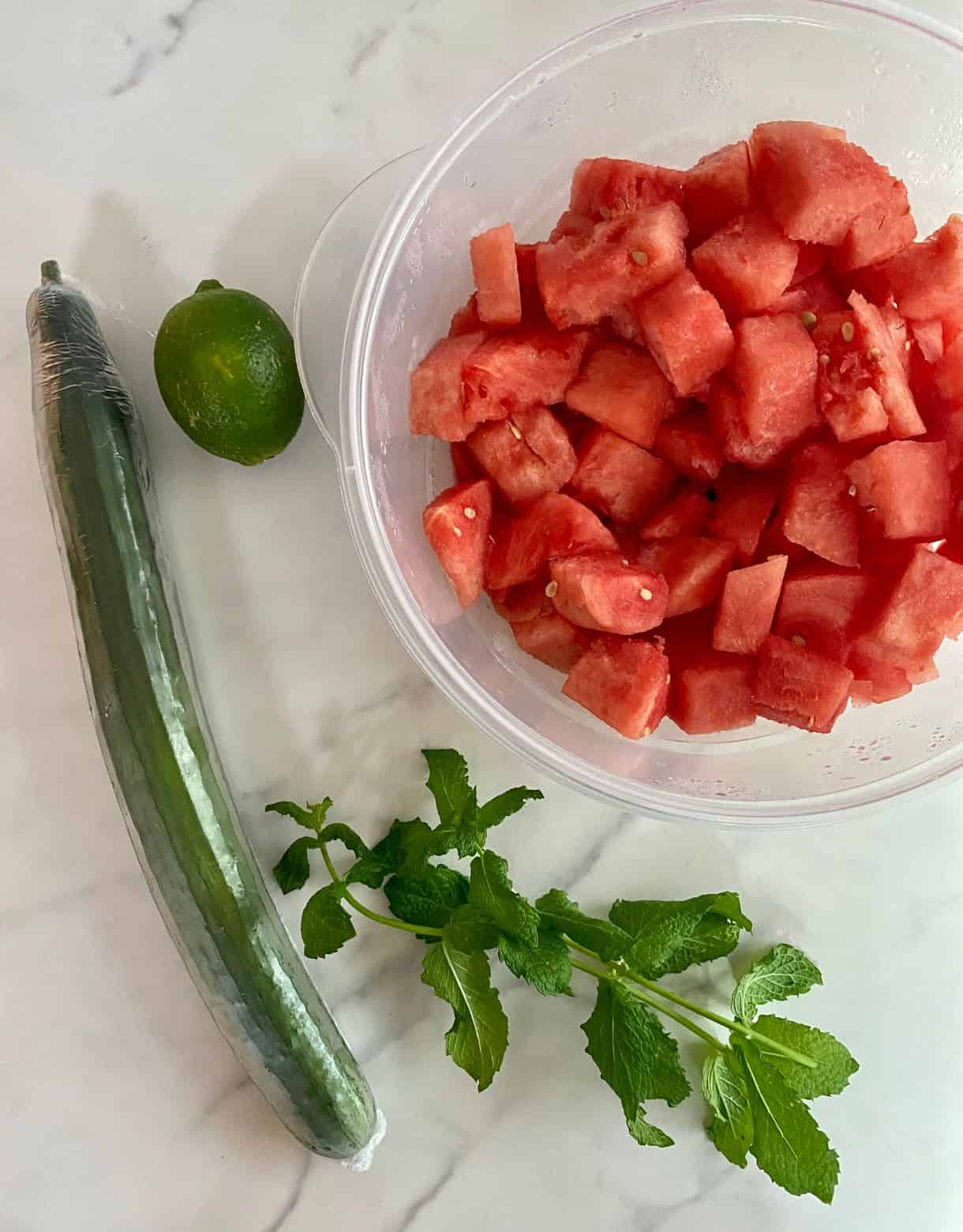 Diced watermelon, a cucumber, a lime, a sprig of fresh mint.