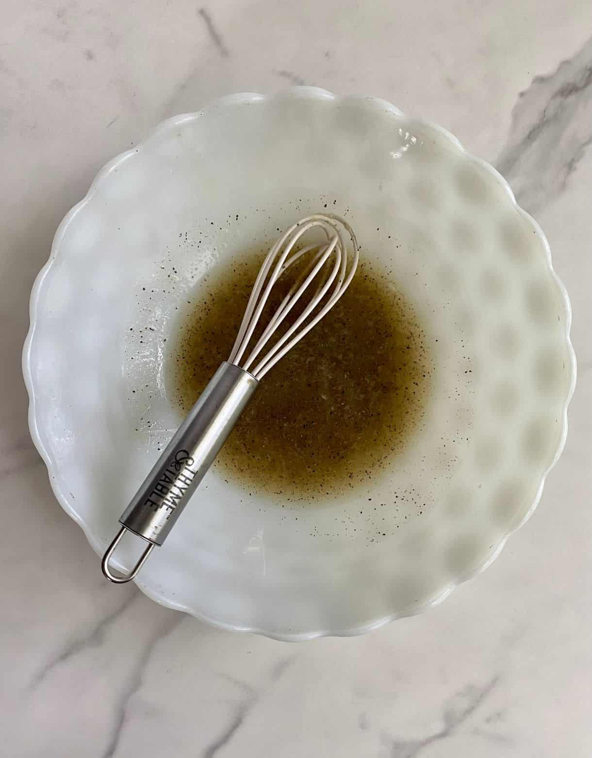 A bowl with a mini whisk and lime juice, salt and pepper mixed togehter in the bowl.