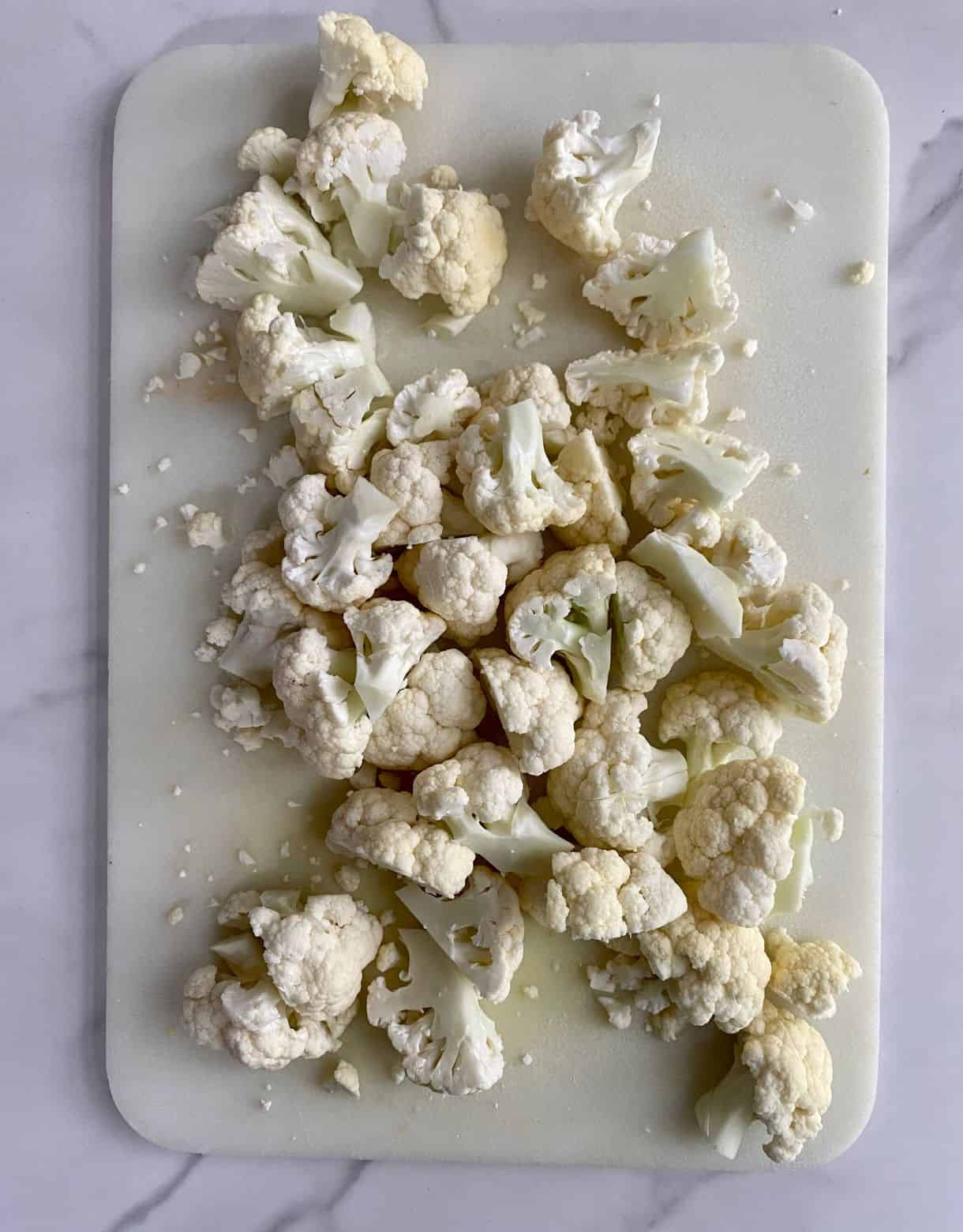 A cutting board with cauliflower cut into florets.