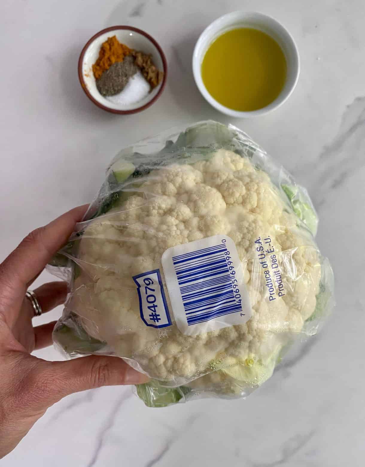 A head of cauliflower, olive oil, salt, pepper, cumin and turmeric.
