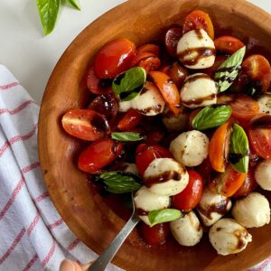 A bowl of Tomato and Bocconcini Salad drizzled with balsamic glaze.