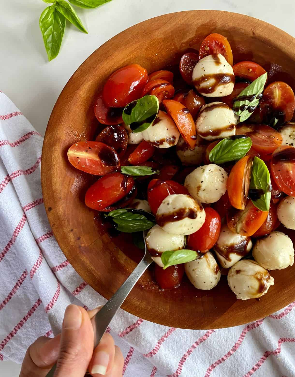 A bowl of Tomato and Bocconcini Salad drizzled with balsamic glaze.