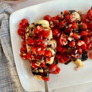 A platter of prepared Sheet Pan Bruschetta Chicken.