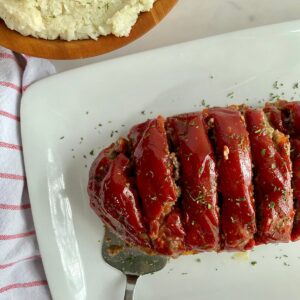 A platter with cooked Parmesan Mealoaf cut into slices.