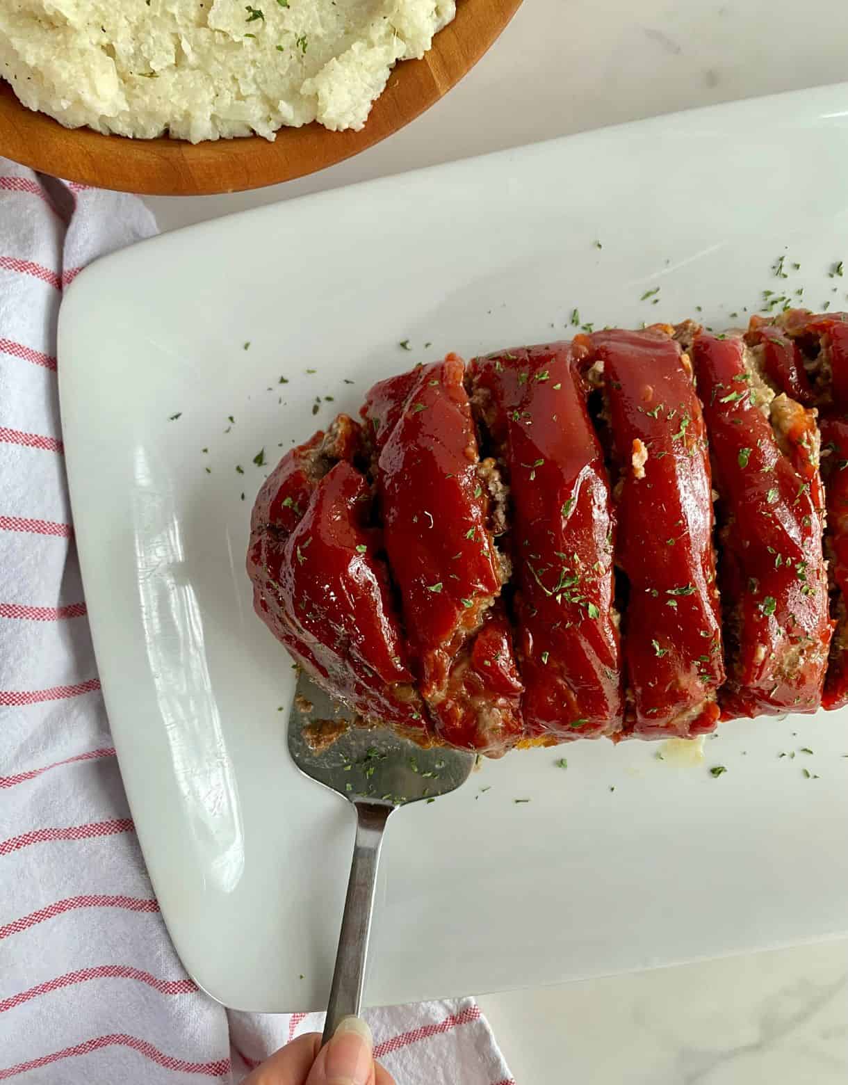 A platter with cooked Parmesan Mealoaf cut into slices.