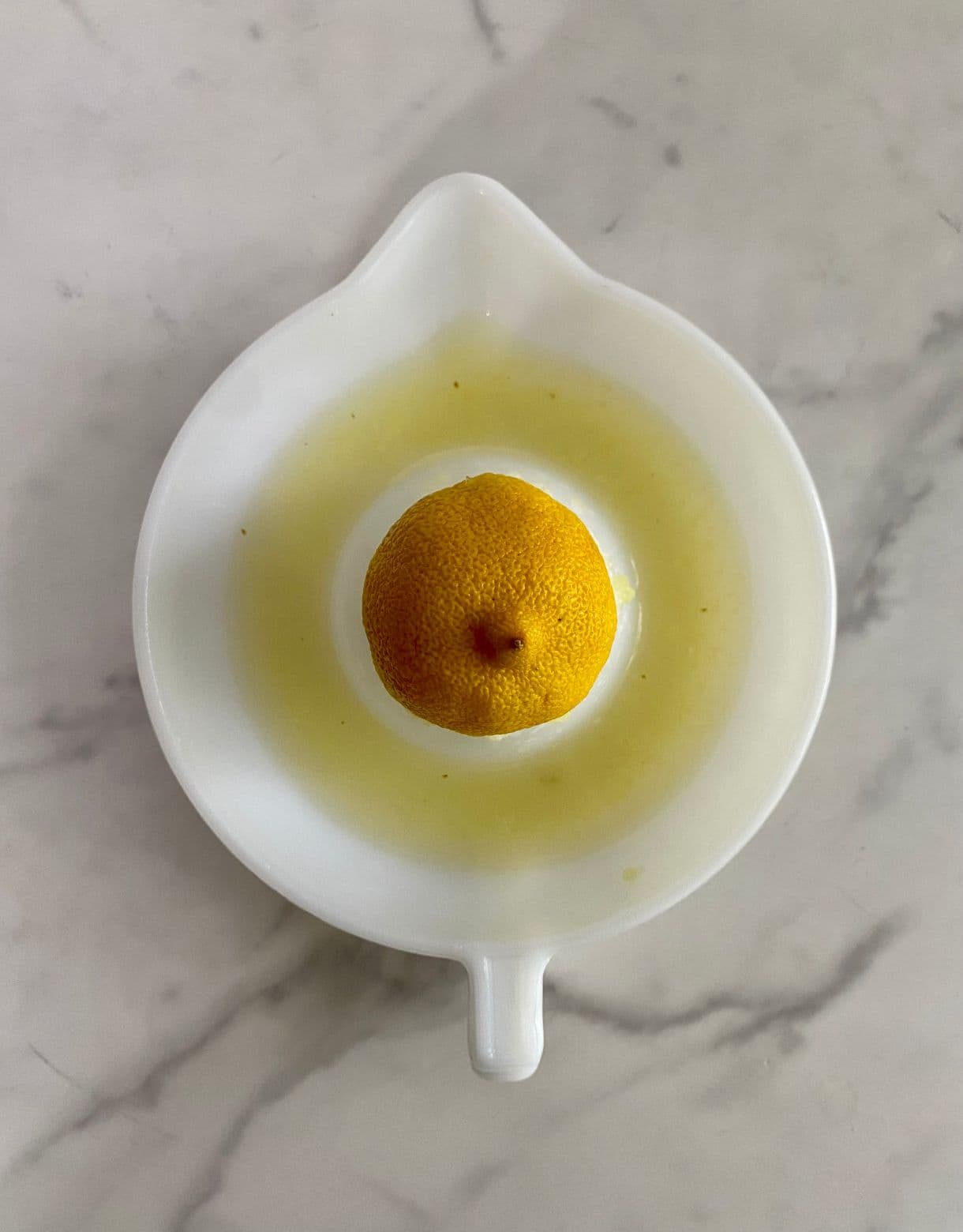 A juice press with half a lemon and lemon juice squeezed out.