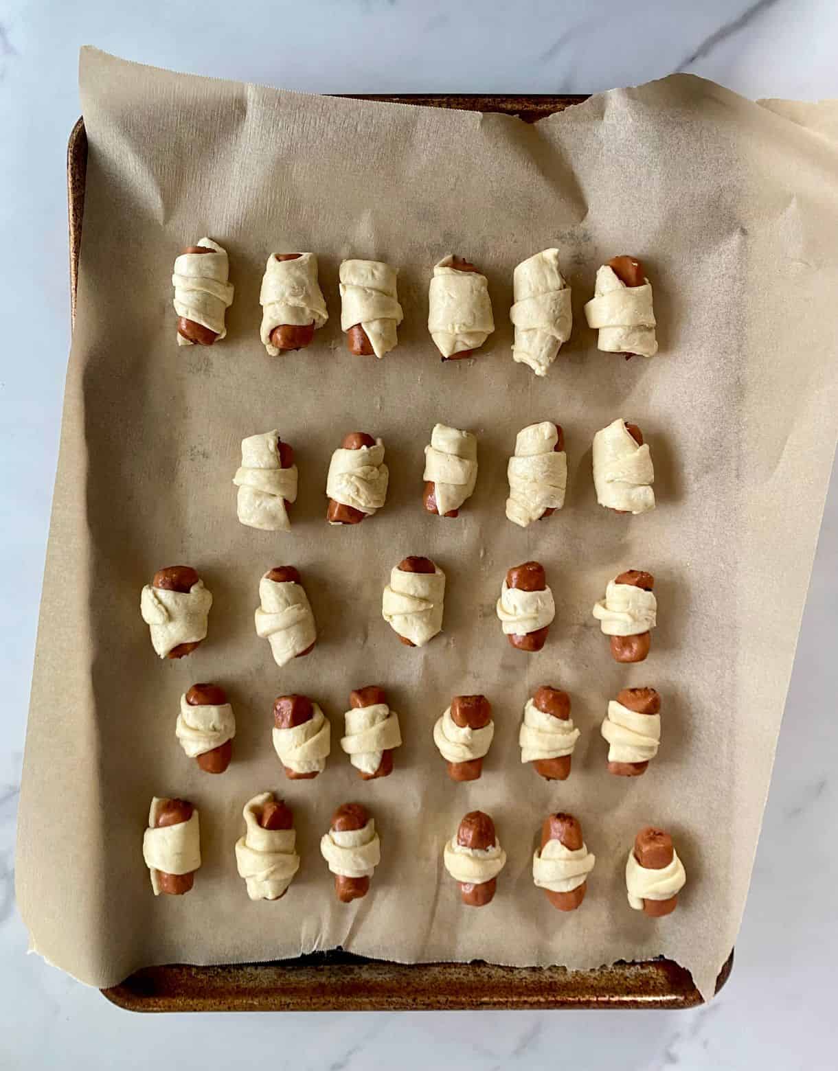 A tray of unbaked pigs in a blanket.
