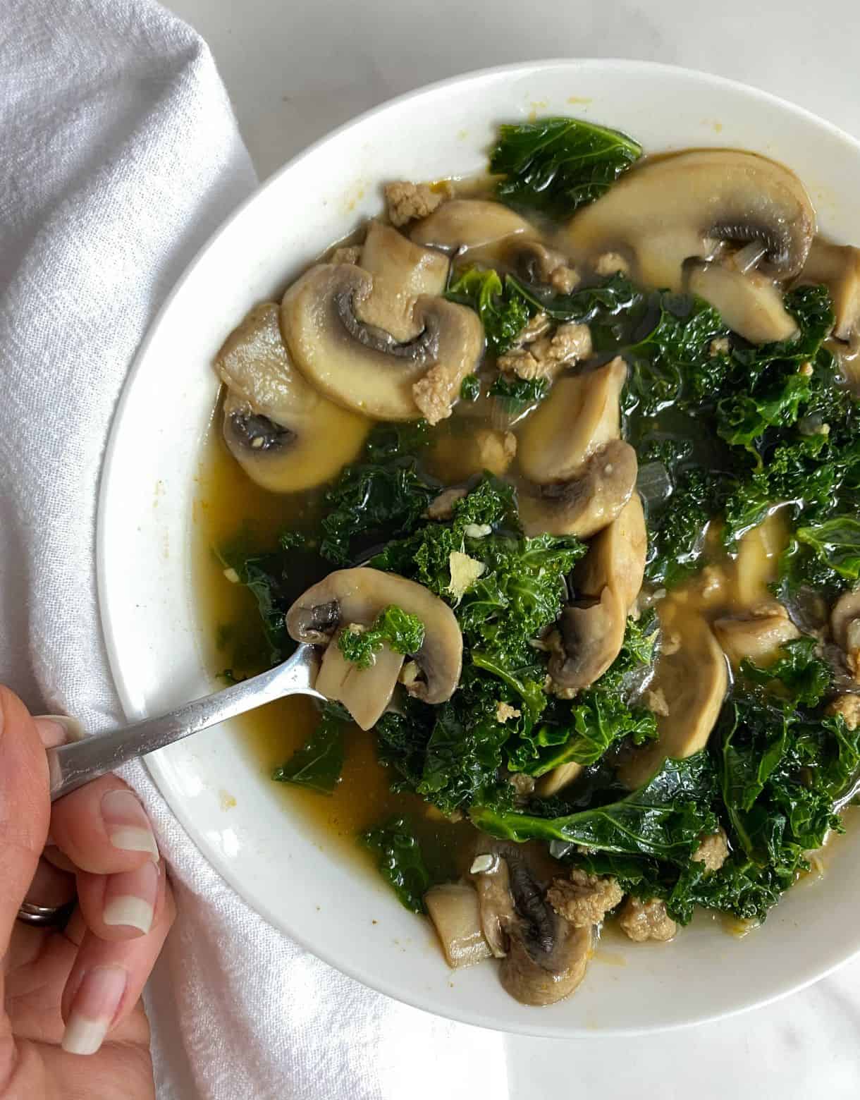 A bowl of Turkey Sausage and Kale Soup with a spoon.