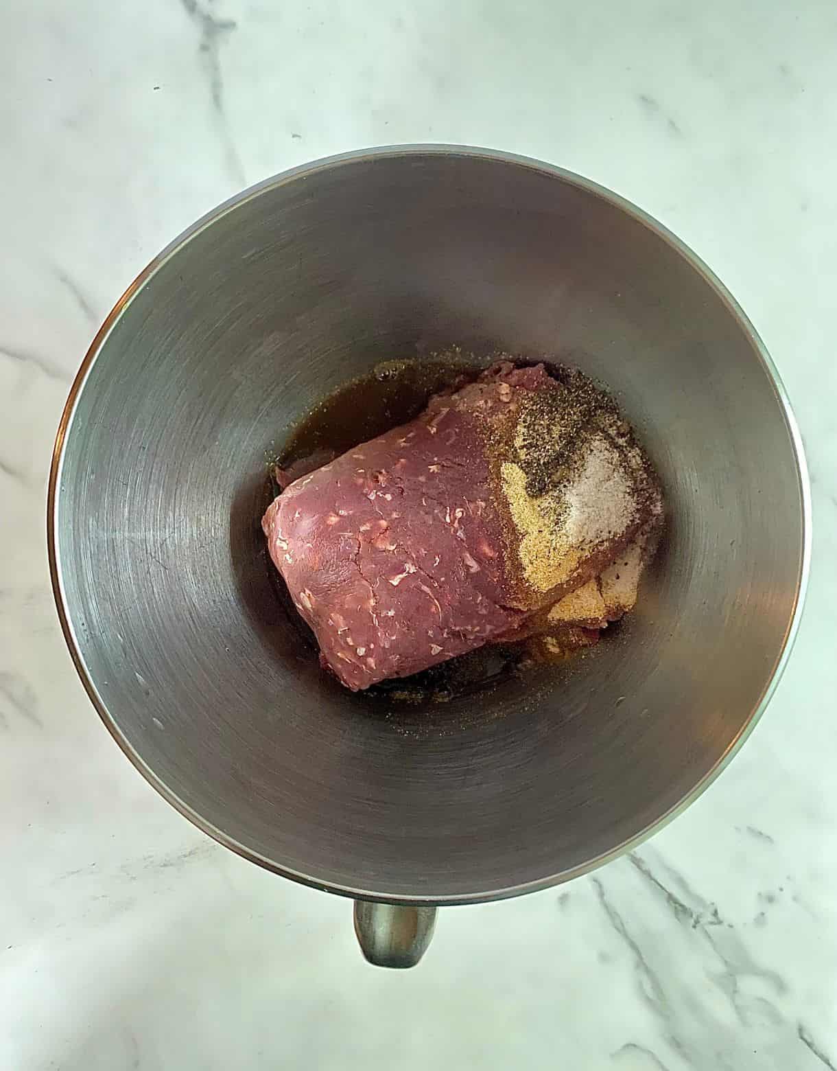 A bowl with ground venison, worcestershire and spices added but not mixed.