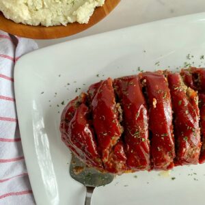 A platter with cooked and sliced Venison Meatloaf on it.