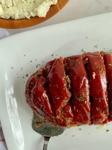 A platter with cooked and sliced Venison Meatloaf on it.