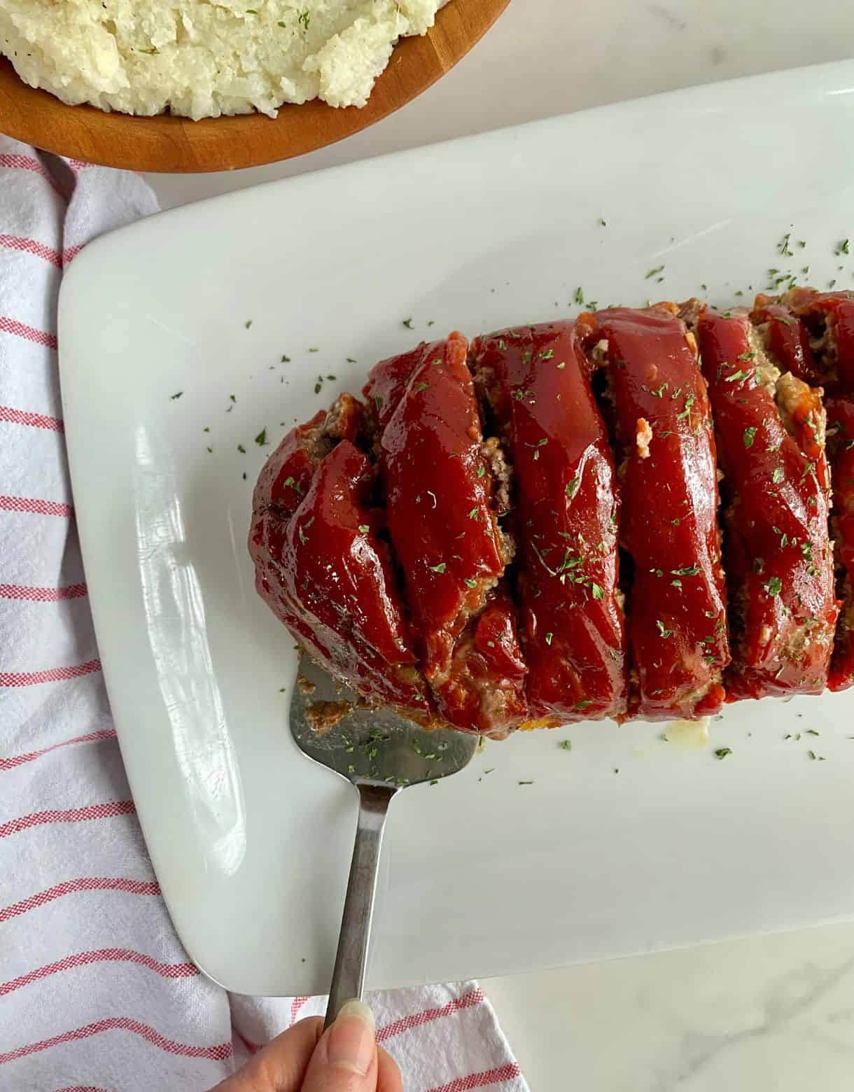 A platter with cooked and sliced Venison Meatloaf on it.