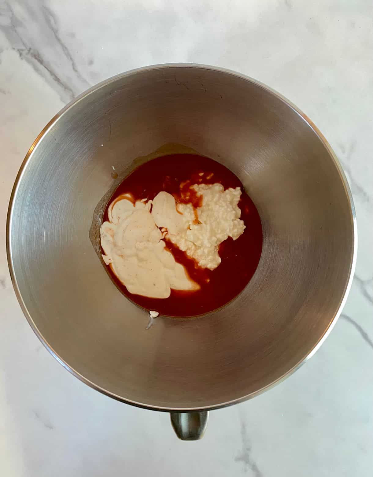 A mixing bowl with ranch and hot sauce added to it.