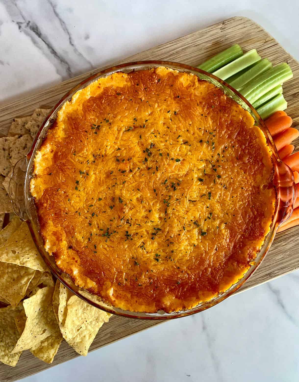 A dish of cooked Cottage Cheese Buffalo Chicken Dip with chips and veggies for dipping.
