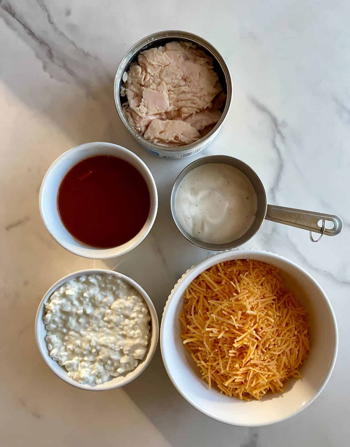 Shredded cheddar cheese, cottage cheese, hot sauce, ranch dressing and cooked chicken.