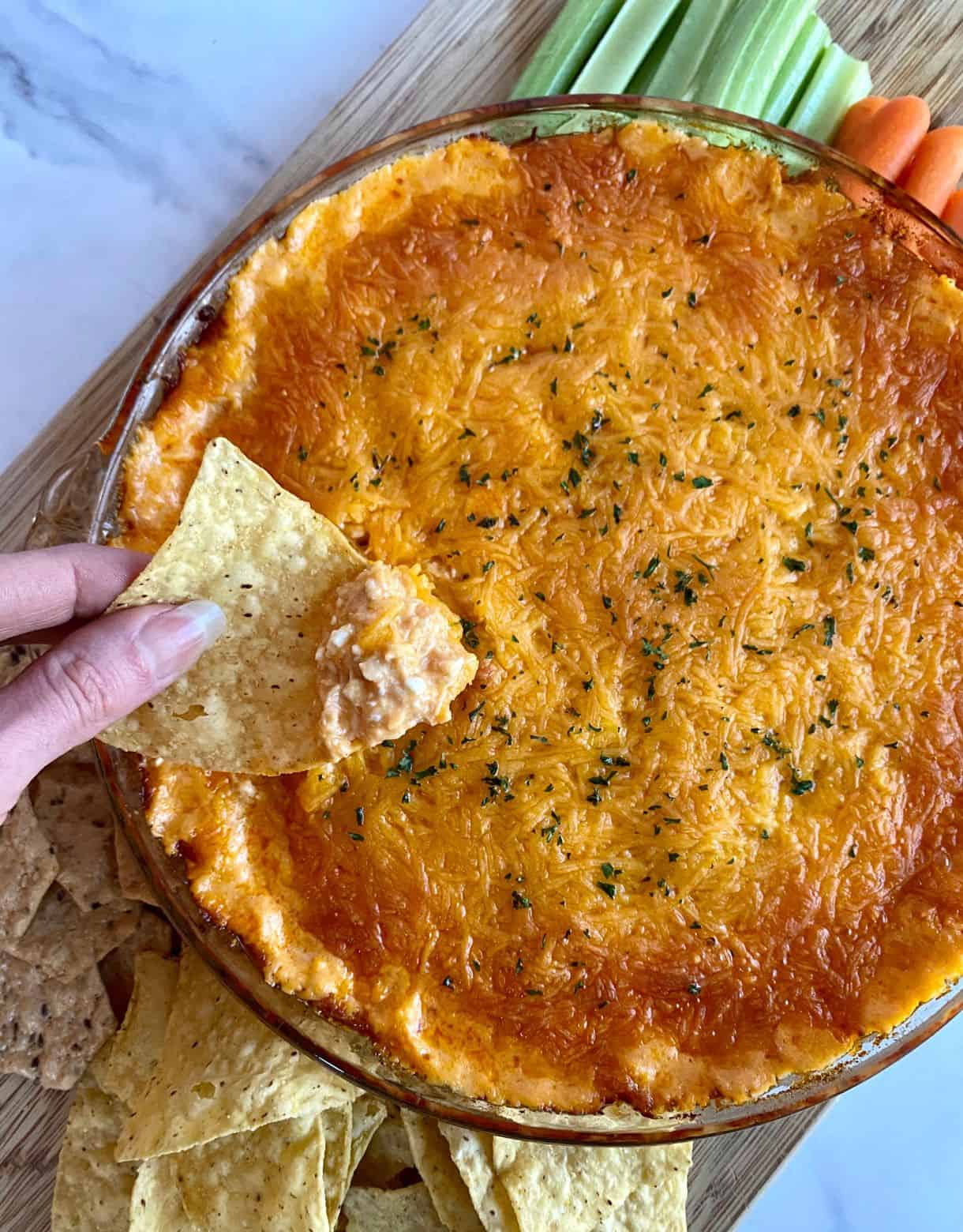 A dish of cooked Cottage Cheese Buffalo Chicken Dip with chips and veggies for dipping.
