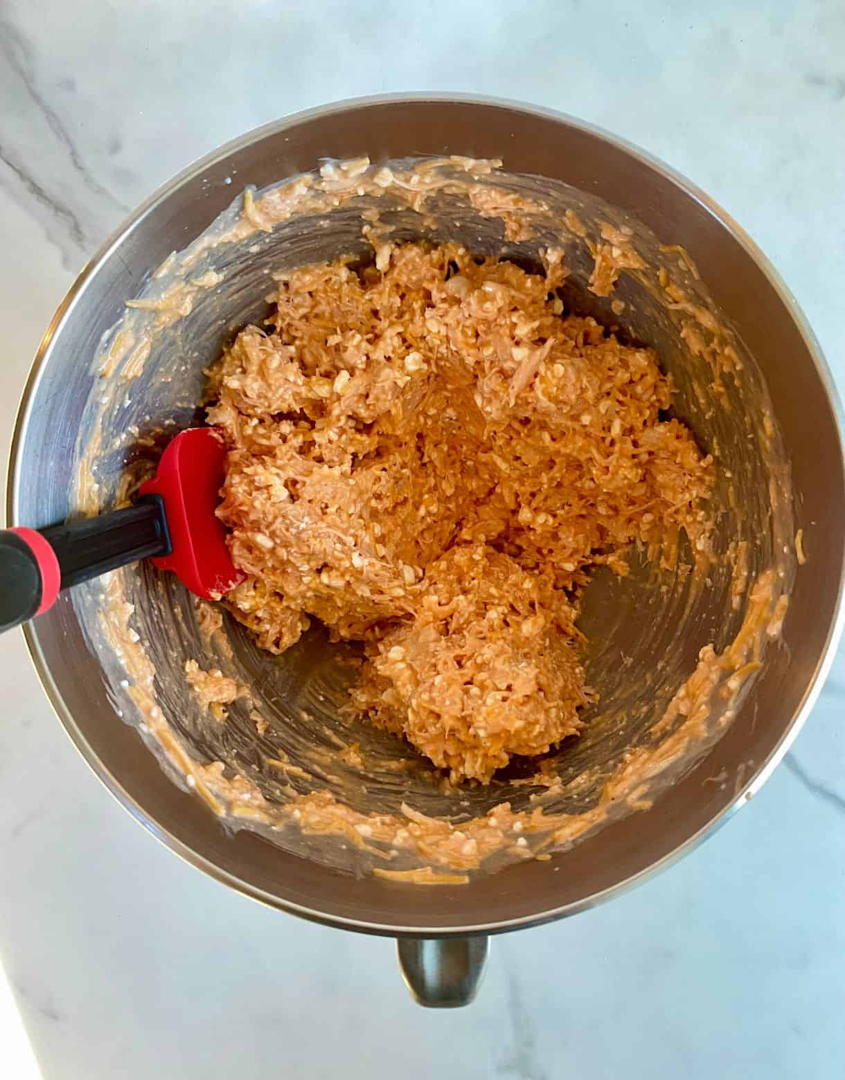 A mixing bowl with a buffalo chicken and cheese mixture in it.