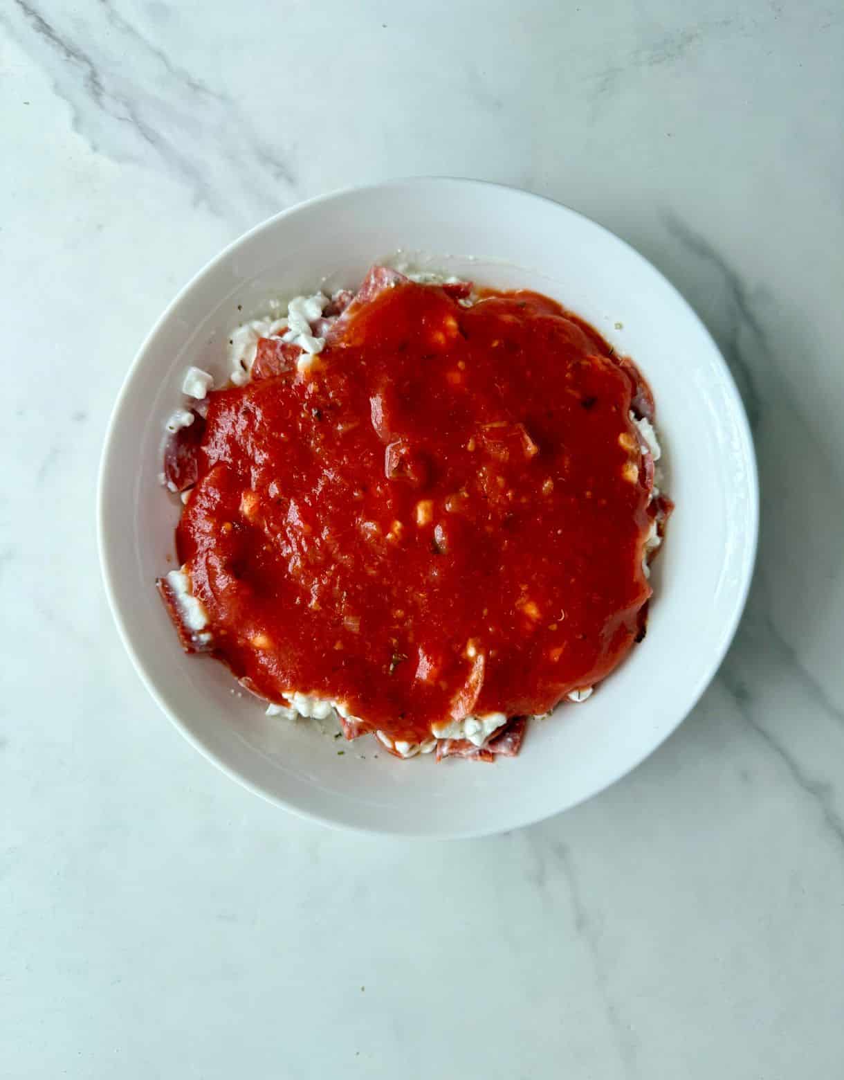 A layer of marinara sauce in a bowl.
