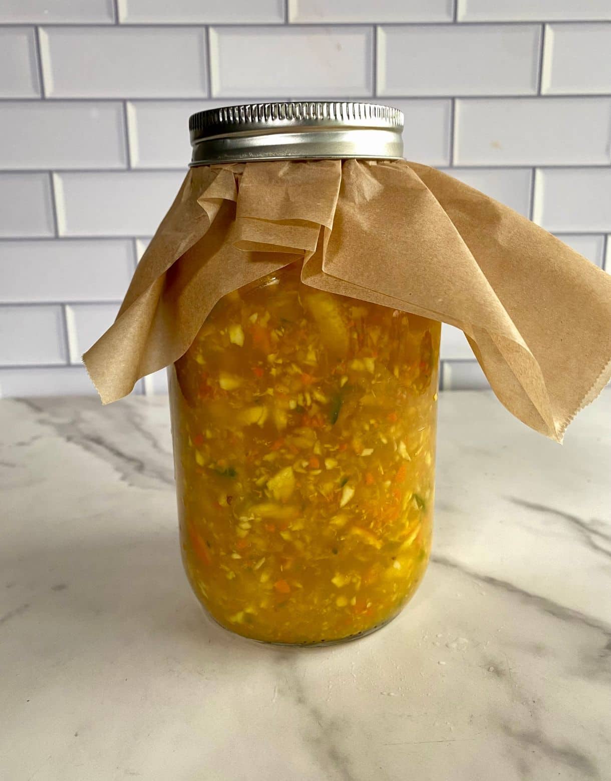 A jar of chopped fruits and vegetables soaking in vinegar.