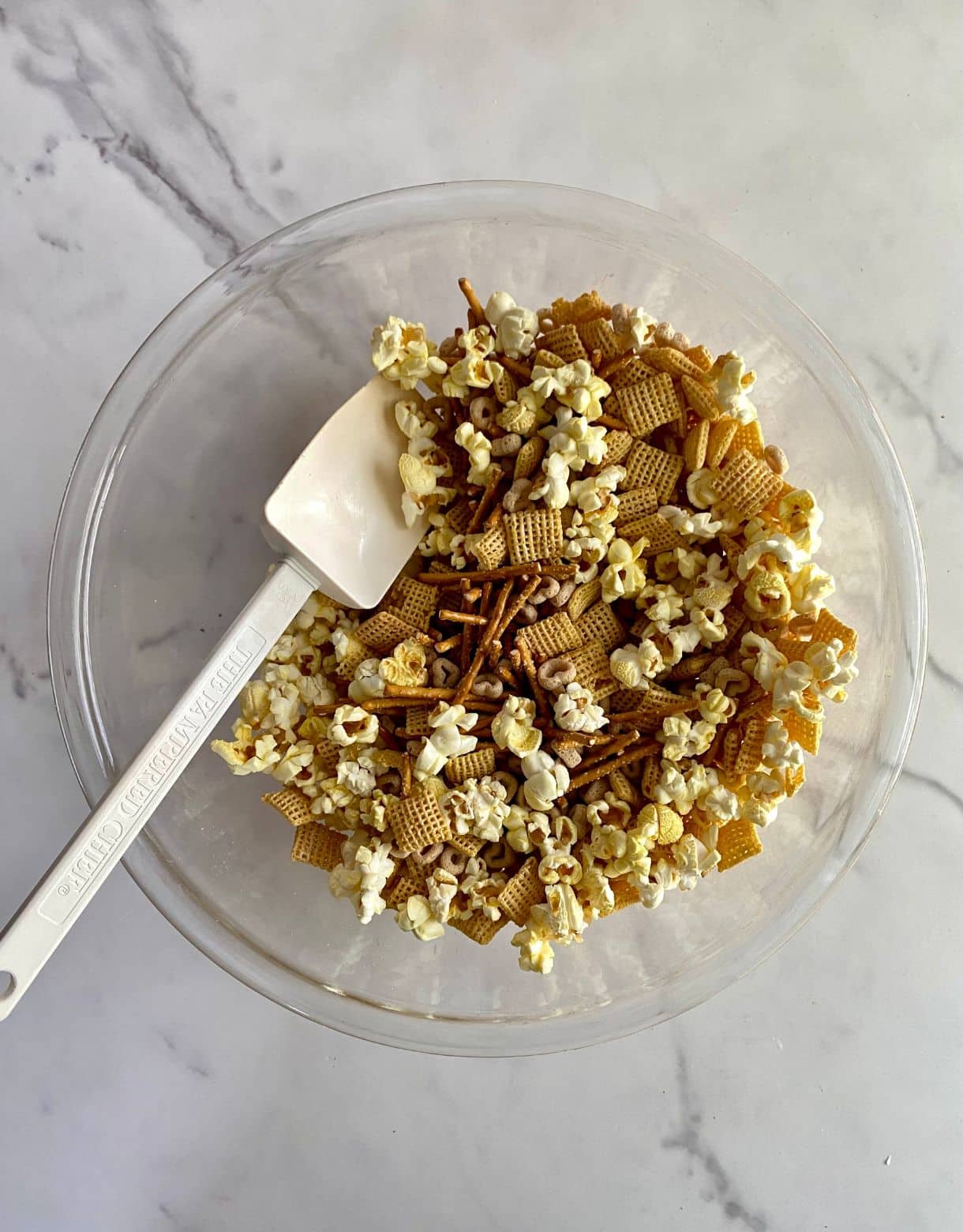 A large bowl with popcorn, pretzels, chex and cheerios mixed together.