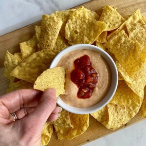 A bowl of cottage cheese queso surrounded by tortilla chips.