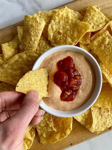 A bowl of cottage cheese queso surrounded by tortilla chips.