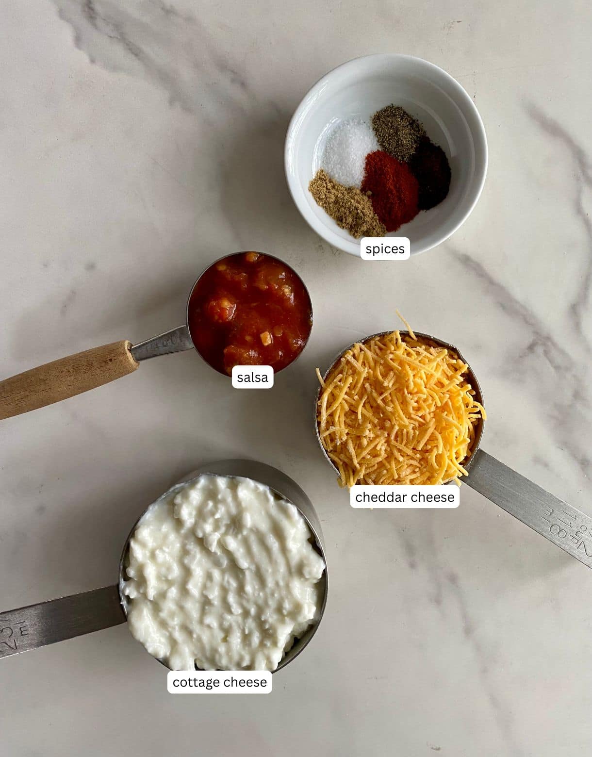 Small bowls of cottage cheese, cheddar cheese, salsa and spices.