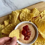 A bowl of cottage cheese queso surrounded by tortilla chips.