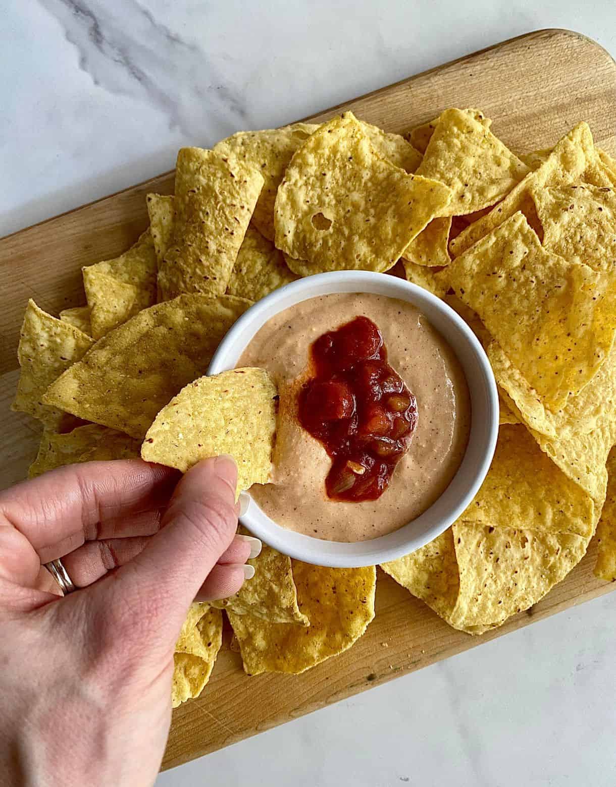 A bowl of cottage cheese queso surrounded by tortilla chips.