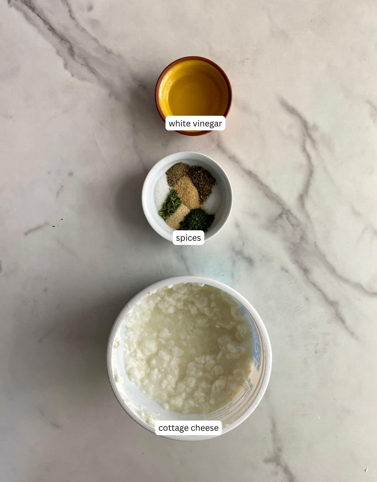 Small bowls of cottage cheese, white vinegar and spices.