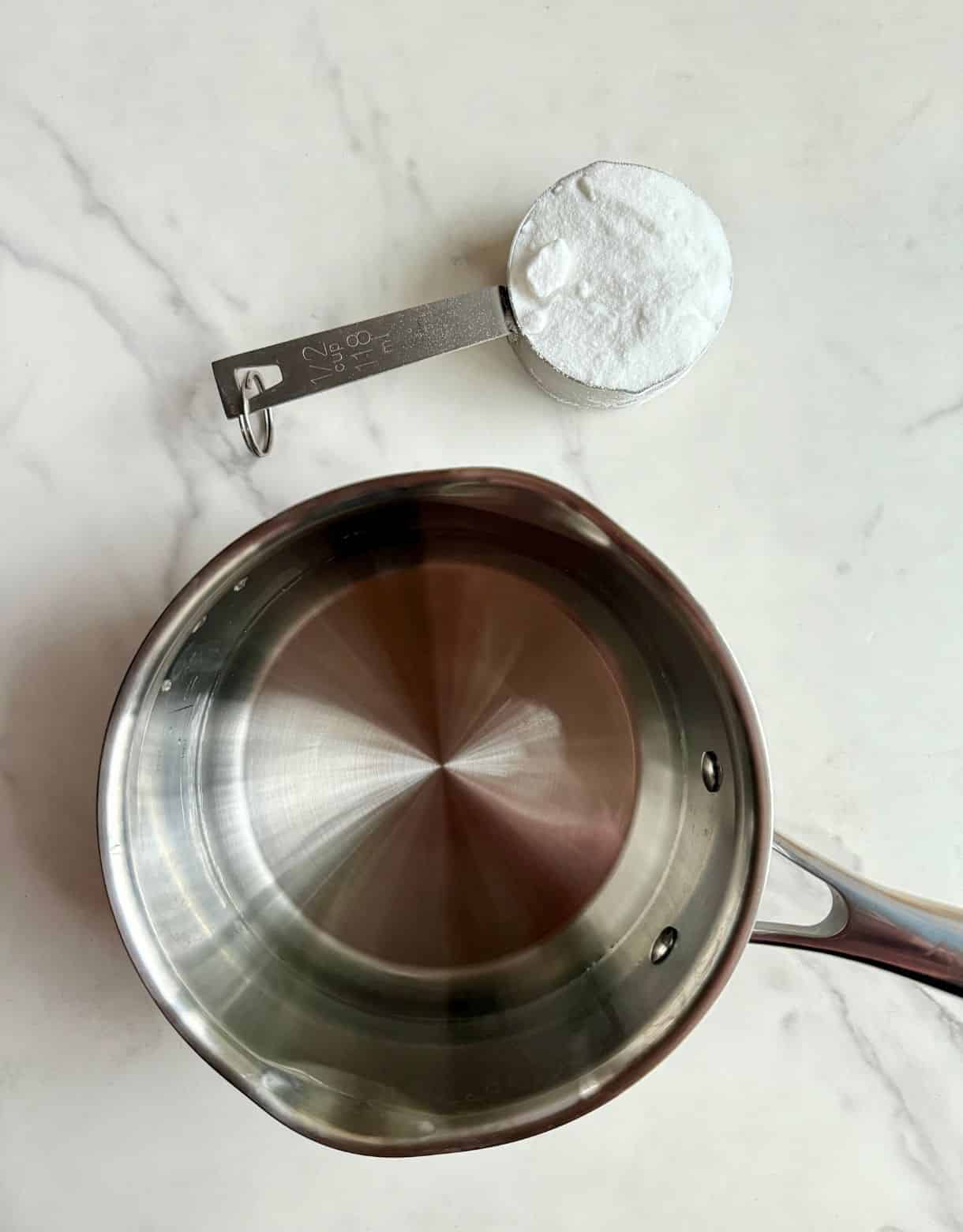 A small pot with water and a cup with sugar-substitute.